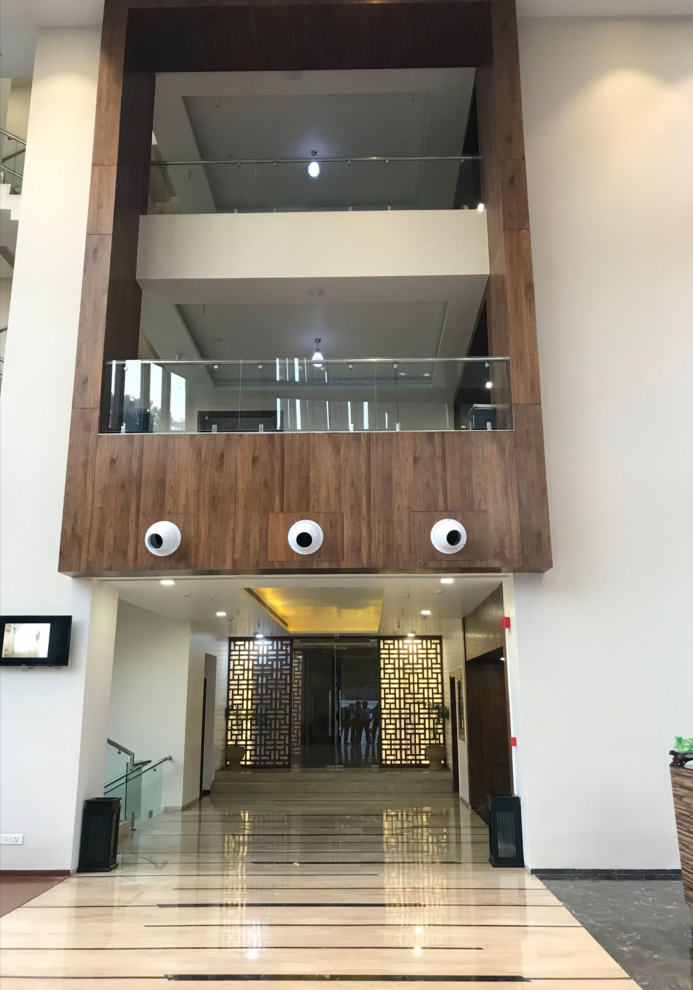 A multi-level interior with a wooden facade, glass railings, and a reflective floor.