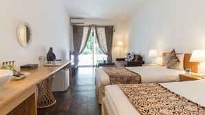 A hotel room with two beds, a desk, a chair, a lamp, and a view of the outdoors.