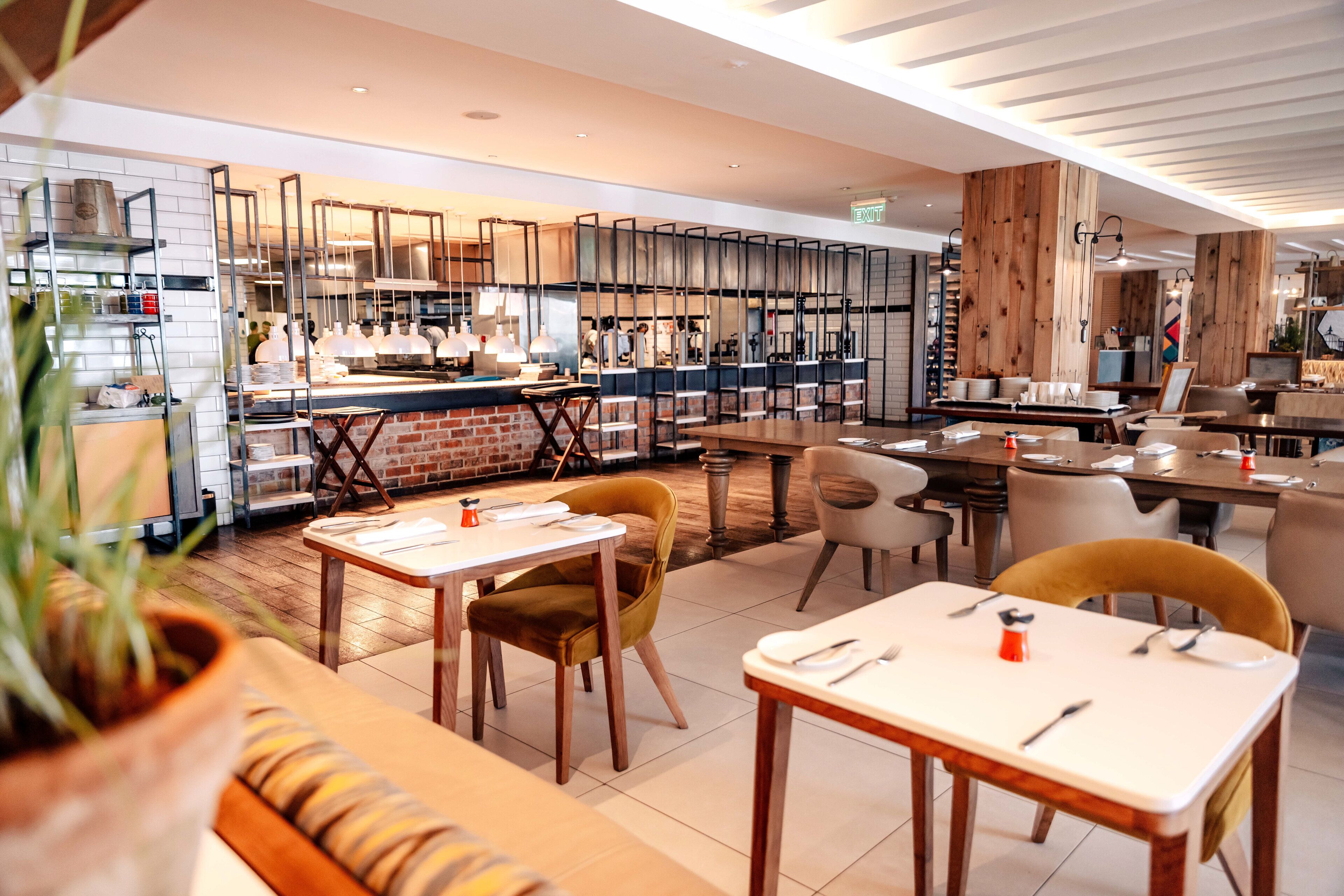 A modern restaurant with a brick wall, wooden accents, and a variety of seating options including tables and chairs.