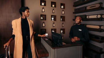 A reception desk with a wooden counter and a wall displaying clocks in square frames.