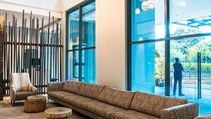 A modern lobby with a long sofa, wooden side tables, and a unique spherical chandelier. - Trademark Hotel (Nairobi)
