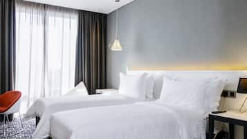 A hotel room with two beds, a chair, a nightstand, and a lamp.