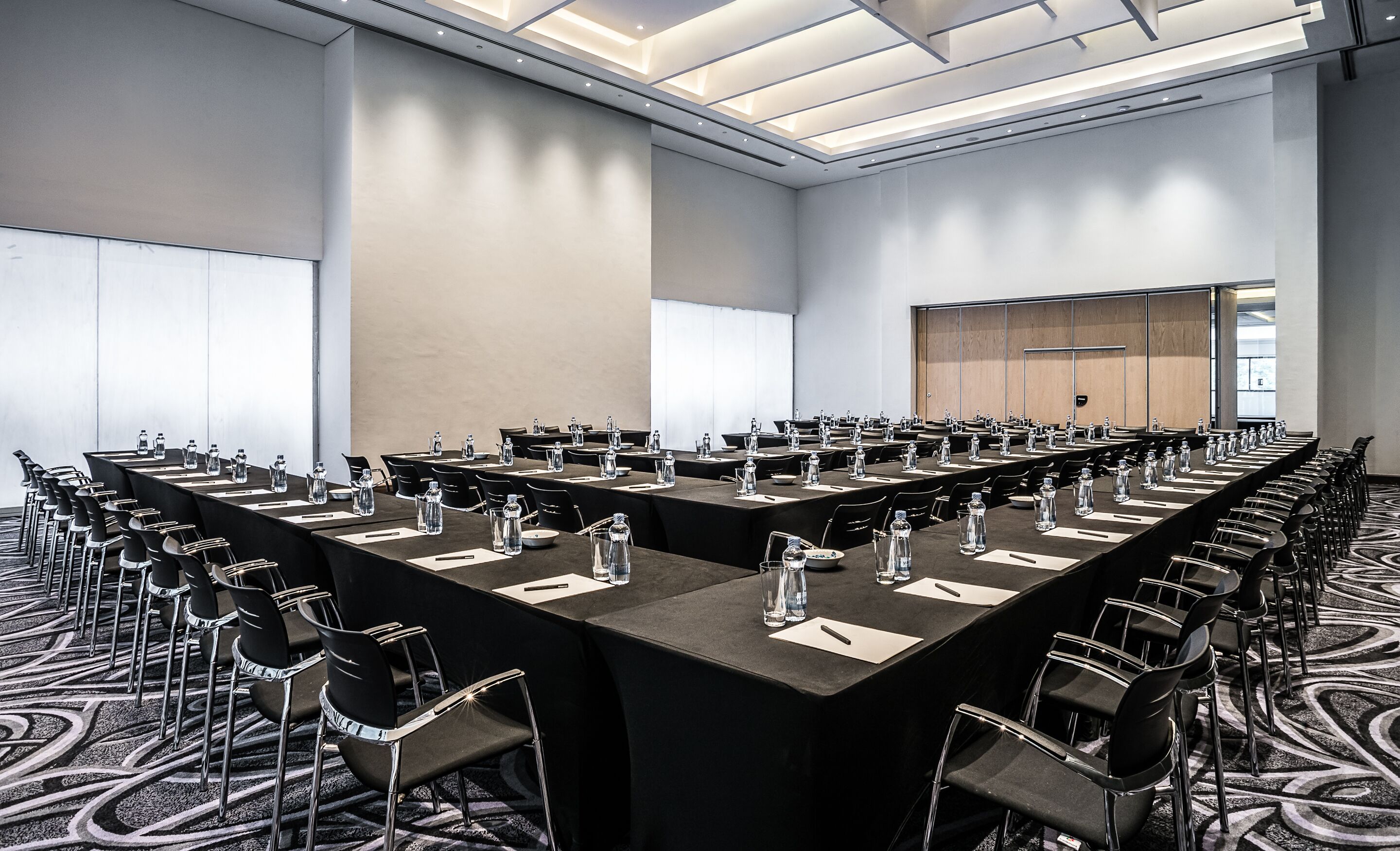 A conference room with long tables, chairs, and water bottles.