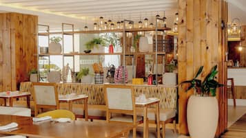 Ein Restaurant mit Holzwandverkleidung, hängenden Pendelleuchten und verschiedenen Pflanzen und Dekorationen auf Regalen.