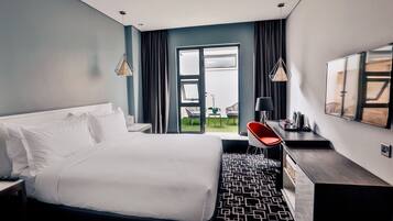 Una habitación de hotel moderna con una cama grande, un escritorio, una silla y vistas al exterior.