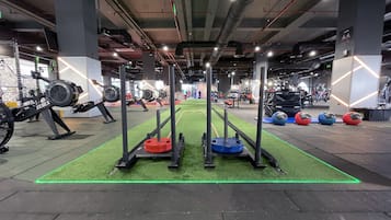 A gym with weightlifting equipment, a green artificial turf area, and various exercise machines.