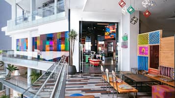 Un espacio interior moderno con barandilla de vidrio, paredes coloridas y diversas opciones de asientos.
