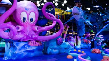 Un grand espace de jeux intérieur, coloré et attrayant, avec différentes structures et décorations sur le thème de la mer.