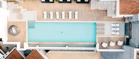 A rooftop pool area with sun loungers, a swimming pool, and a bar area.