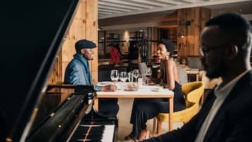 A piano in a room with wooden walls and a dining table with chairs.