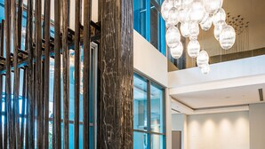 A spacious lobby with a modern design, featuring a sectional sofa, round coffee tables, and a unique wooden partition. - Trademark Hotel (Nairobi)