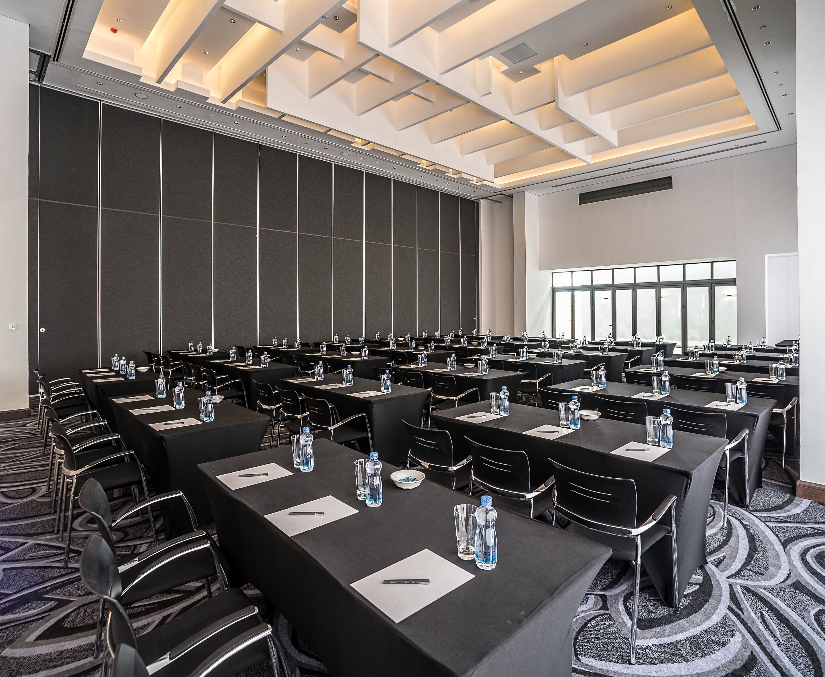 A conference room with rows of tables and chairs, equipped with water bottles and nameplates.
