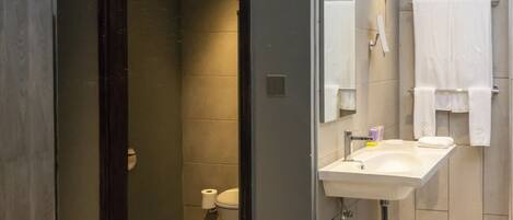 A modern bathroom with a dark shower enclosure, a sink with a mirror, and a toilet.