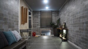 A modern living room with a sofa, a fireplace, and a tiled wall. - Art N Stay - Hostel (Suncheon)