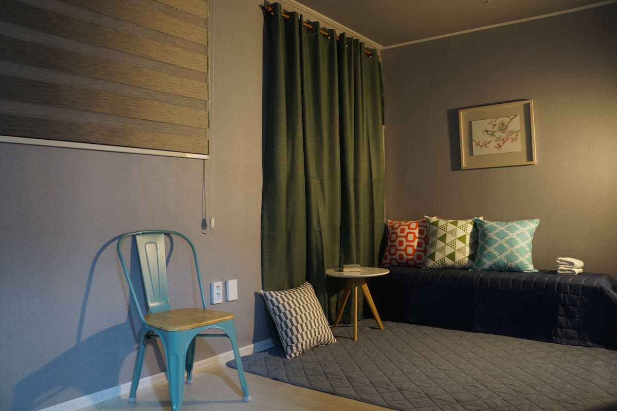 Une pièce comprenant un lit, une chaise, une petite table et un rideau.
