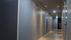 A modern hallway with a tiled floor, grey walls, and doors on both sides. - Art N Stay - Hostel (Suncheon)