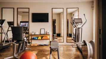 Un gimnasio con equipo de ejercicio, cinta de correr, bicicleta estática y espejo.