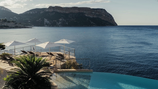 Una piscina infinita con vistas al mar y a las montañas.