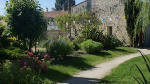 A stone building with a garden path leading to a door. - Du coq à l'âne (Saint-Georges-de-Rex)