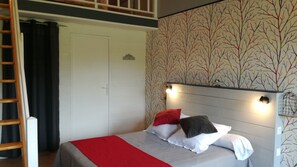 Un dormitorio con cama, una escalera, un armario y un muro decorado con un diseño de árbol.