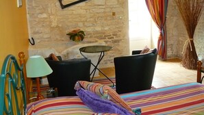 A cozy room with a bed, two chairs, a small table, and a lamp. - Du coq à l'âne (Saint-Georges-de-Rex)