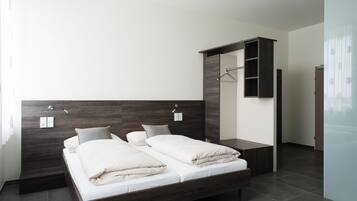 Una camera da letto moderna con un letto grande, una testiera in legno scuro e un armadio a muro.