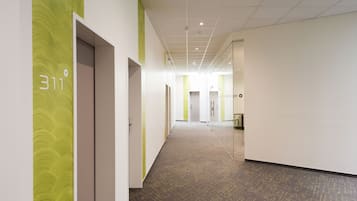 A modern hallway with a carpeted floor, a green accent wall, and a door labeled '311'.