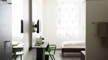 Ein modernes Hotelzimmer mit einem Bett, einem Schreibtisch mit Stuhl, einem Spiegel und einem Vorhangfenster.