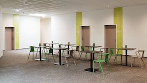 Een moderne, overdekte ruimte met meerdere tafels en stoelen die in een raster zijn geordend.