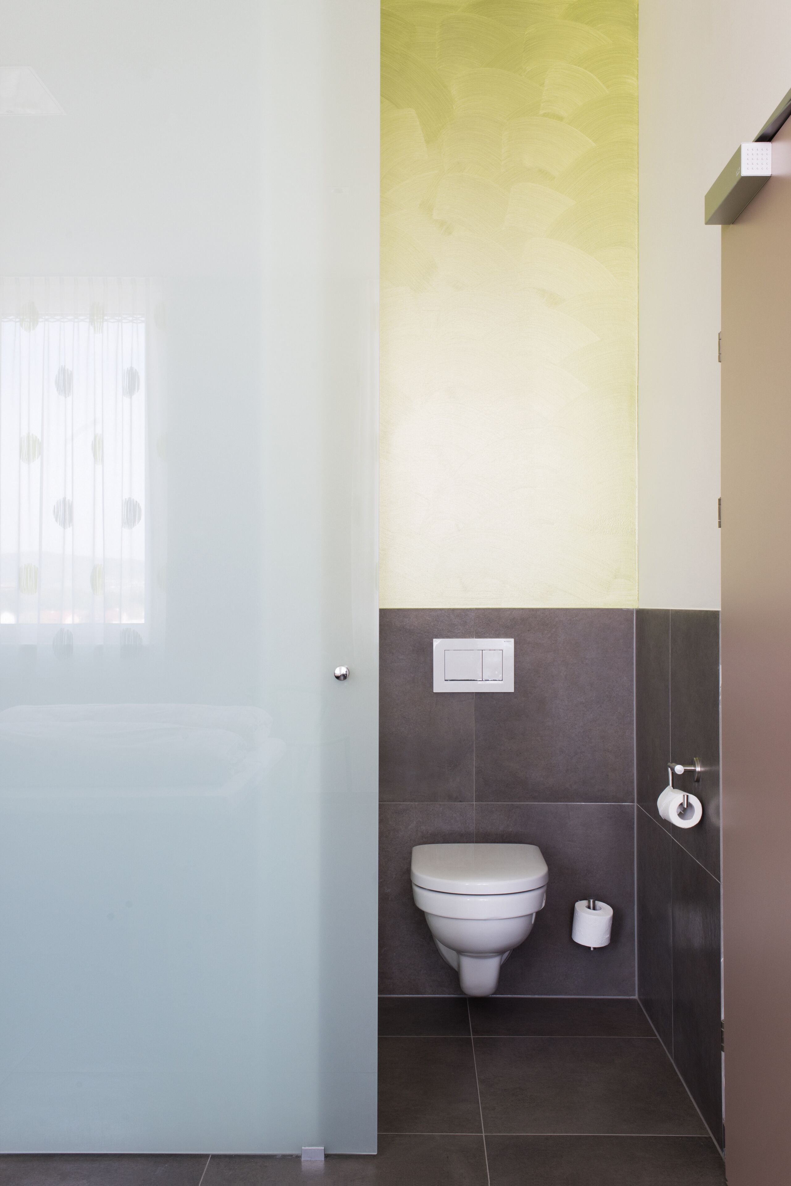 A bathroom with a toilet, a towel rack, and a toilet paper holder.