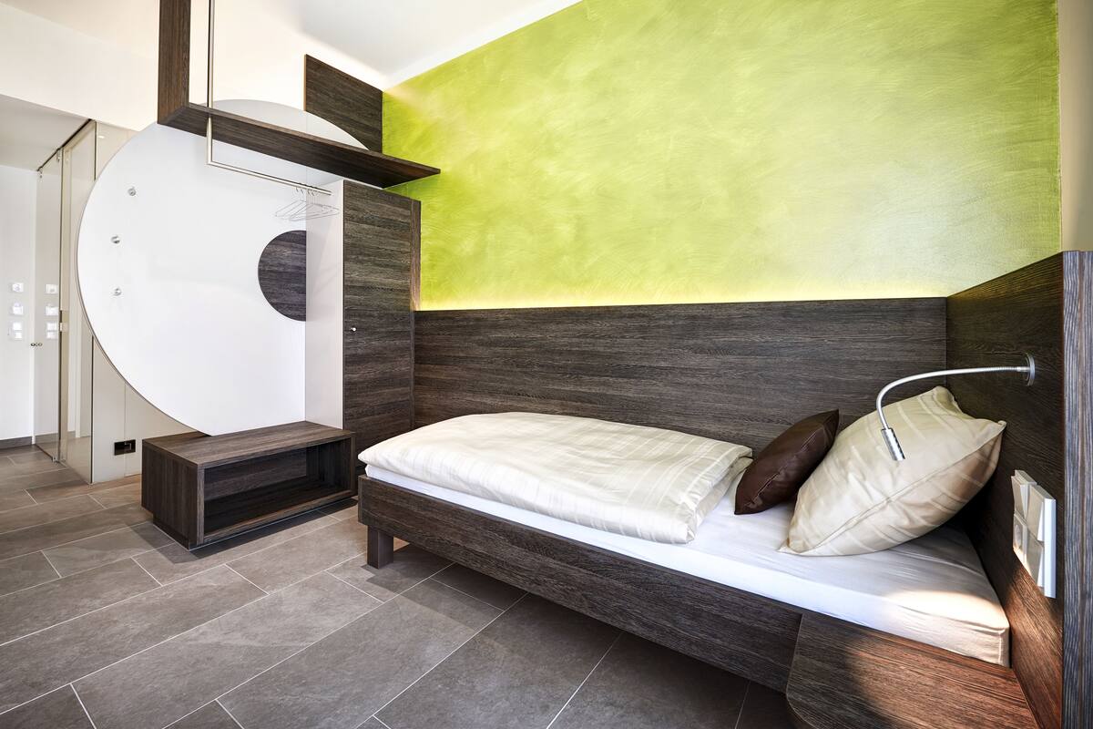 A modern bedroom with a built-in bed, a wardrobe, and a circular mirror.
