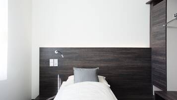 Une chambre à coucher moderne avec une tête de lit en bois foncé, une couvre-lit blanche et un seul oreiller gris.