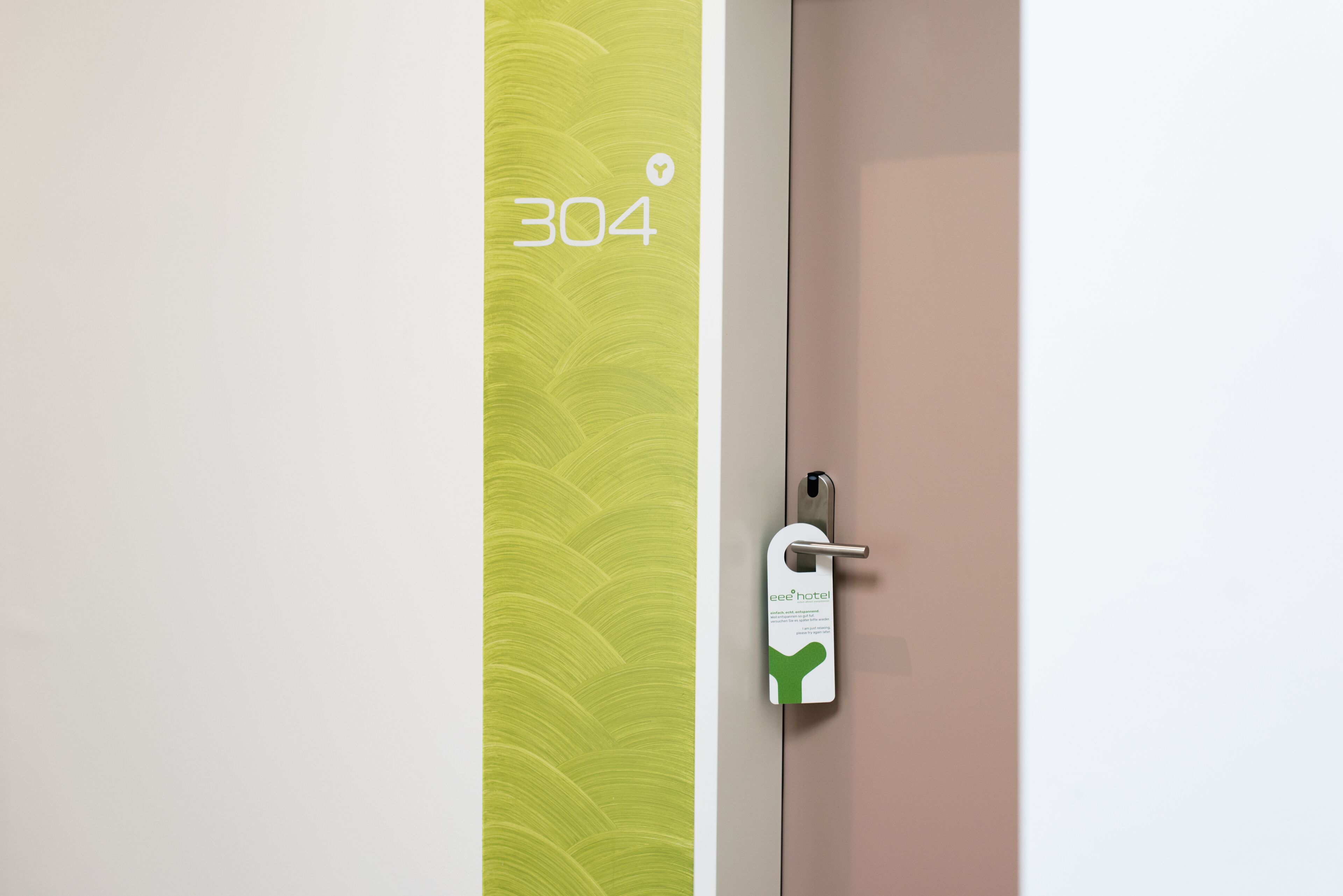 A hotel room door with a green wall and a door number 304.