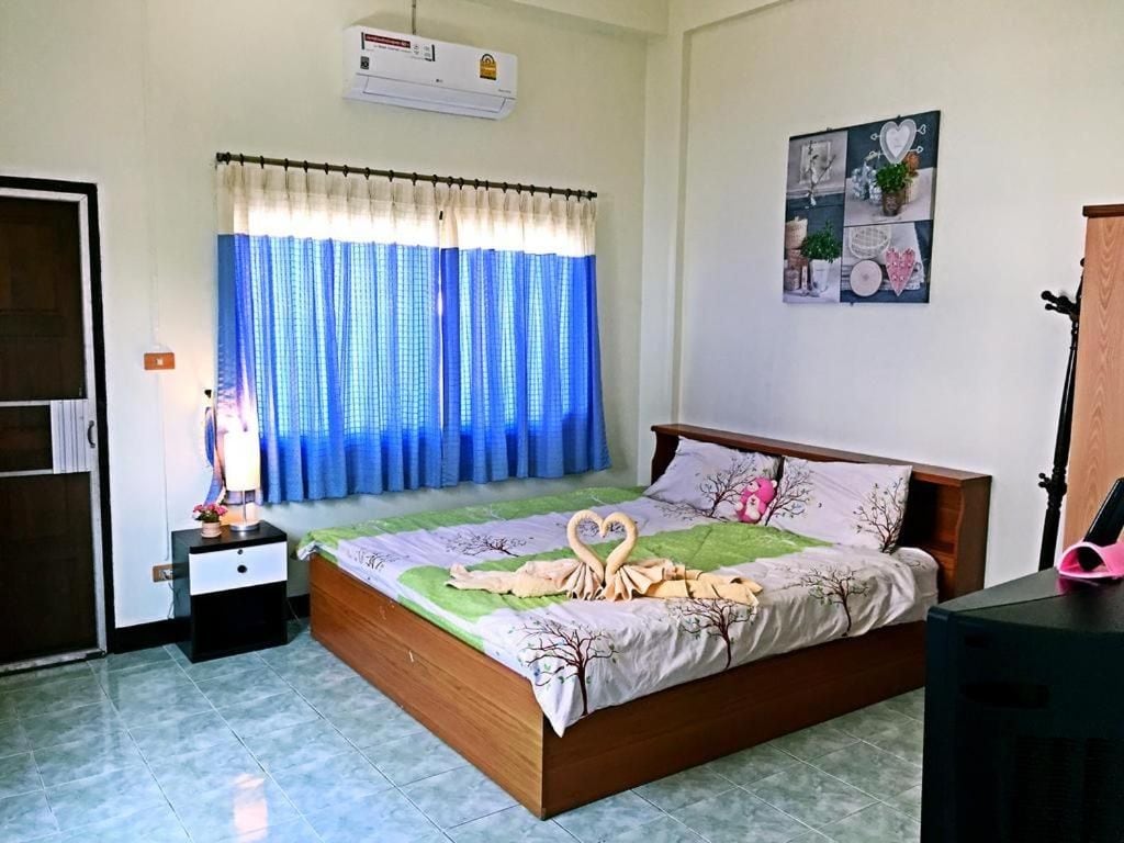 Un dormitorio con cama, mesita de noche, aire acondicionado de pared, ventana con cortinas y decoración en la pared.