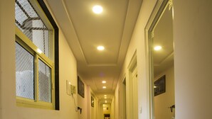A long, narrow hallway with a polished granite floor, white walls, and a series of doors on one side.