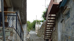 Una escalera de piedra que sube hacia un edificio, con barandilla de metal a la derecha y de madera a la izquierda.