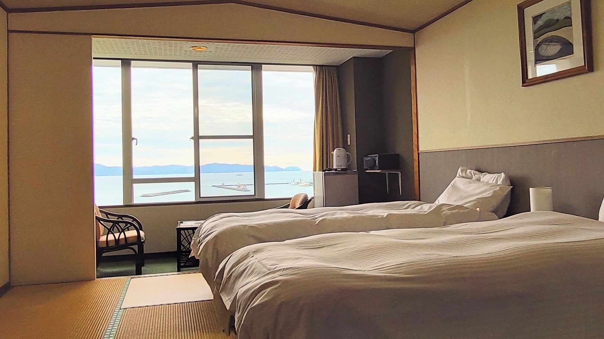 A hotel room with two beds, a window with a view, a desk, and a chair.