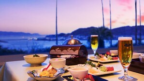 A table set for a meal with a view of palm trees and a sunset. - Ibusuki Phoenix Hotel (Ibusuki)