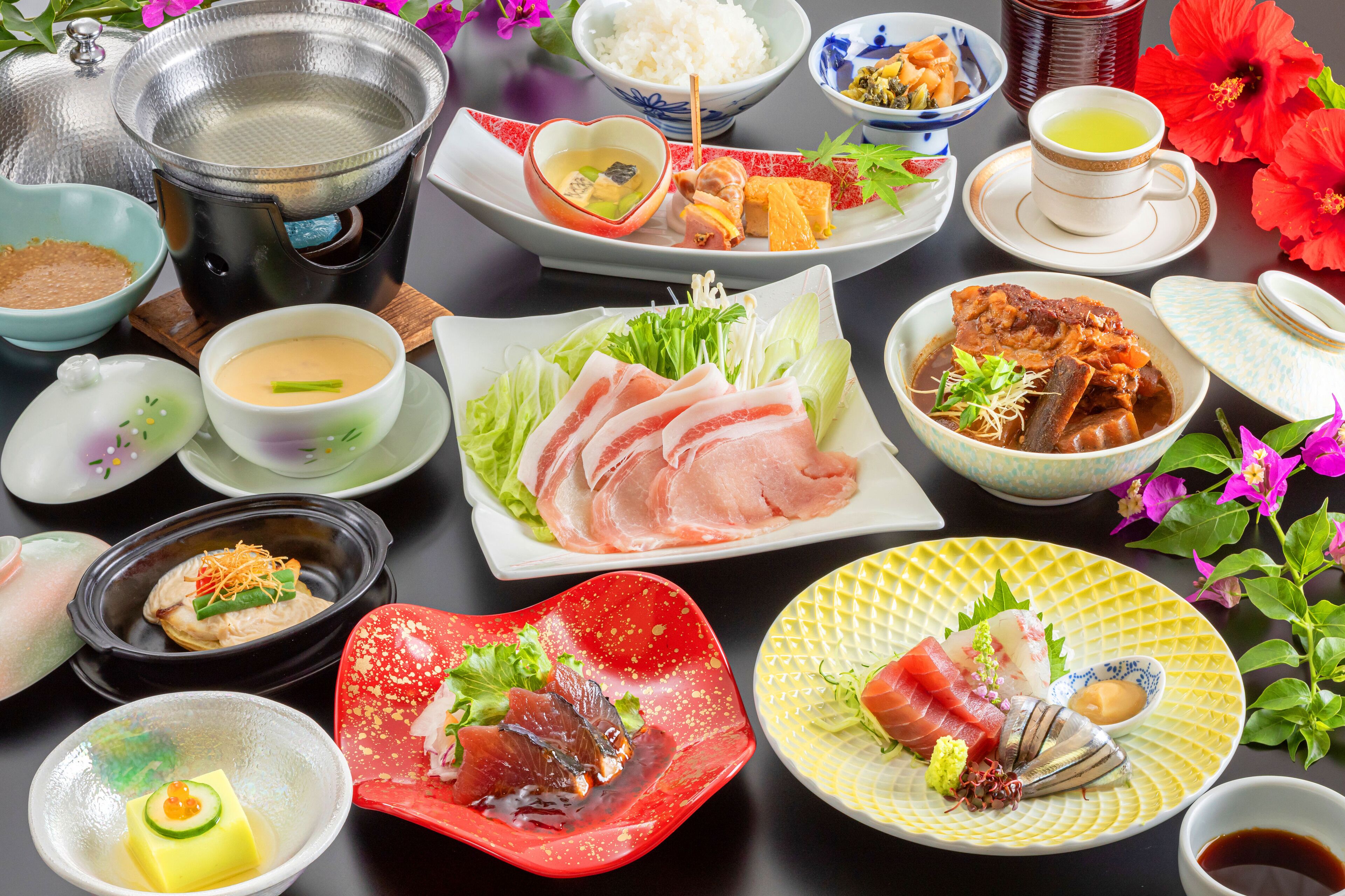 A variety of Japanese dishes including sushi, sashimi, and tempura, served on multiple plates and bowls.