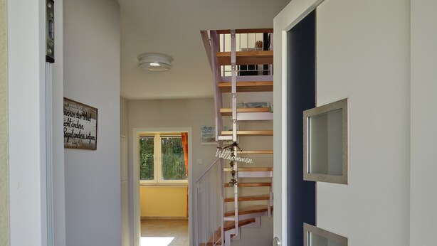 Un escalier avec des marches en bois et une rampe métallique menant à un palier.