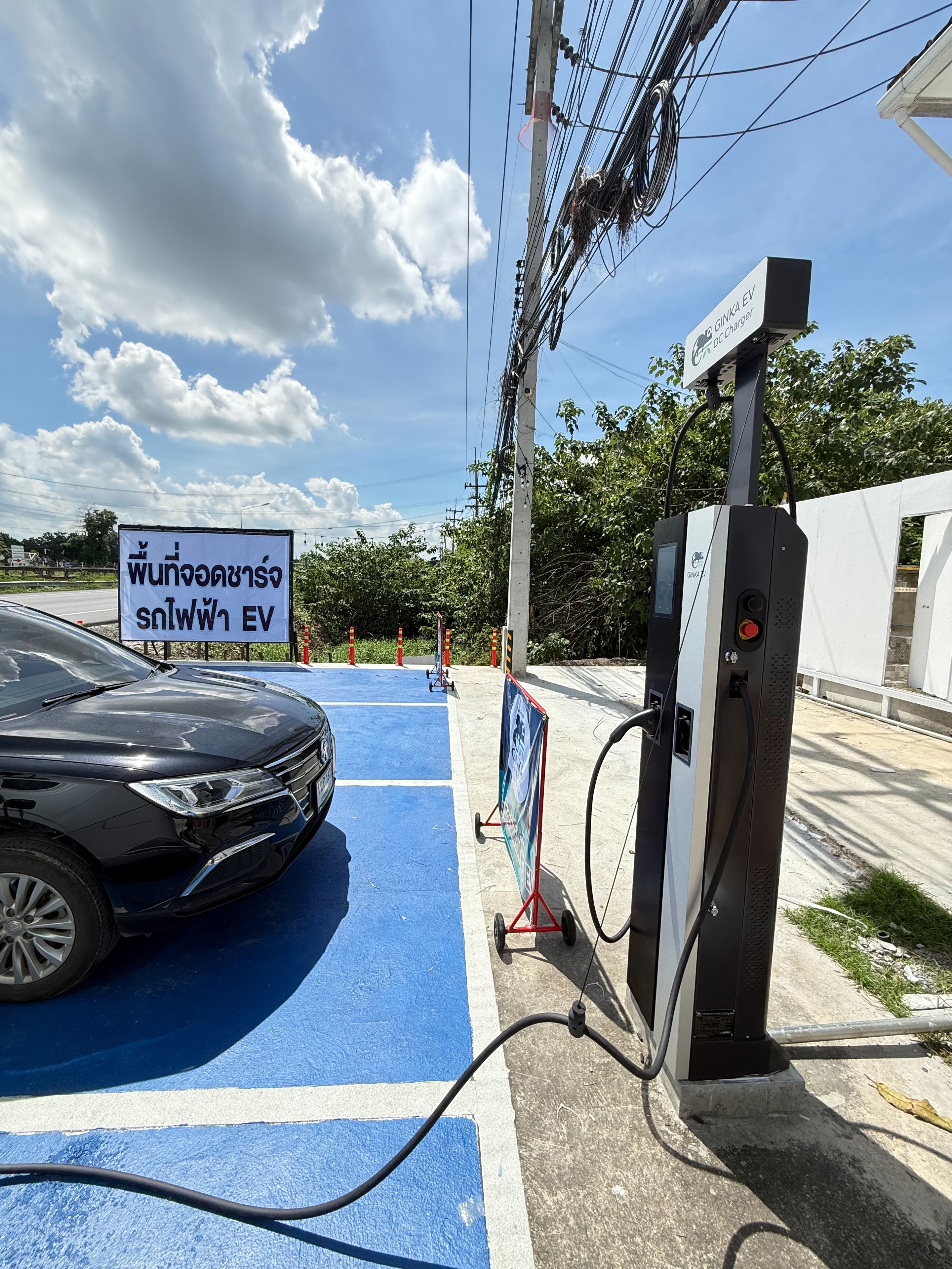 Une borne de recharge pour véhicules électriques avec une voiture garée dans une place de stationnement bleue.