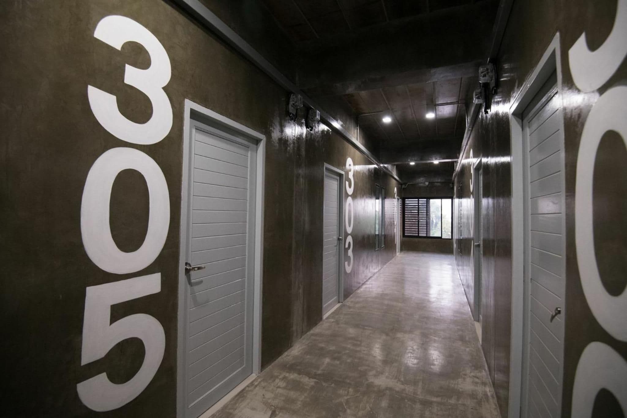 A corridor with doors marked with numbers, likely indicating hotel rooms.