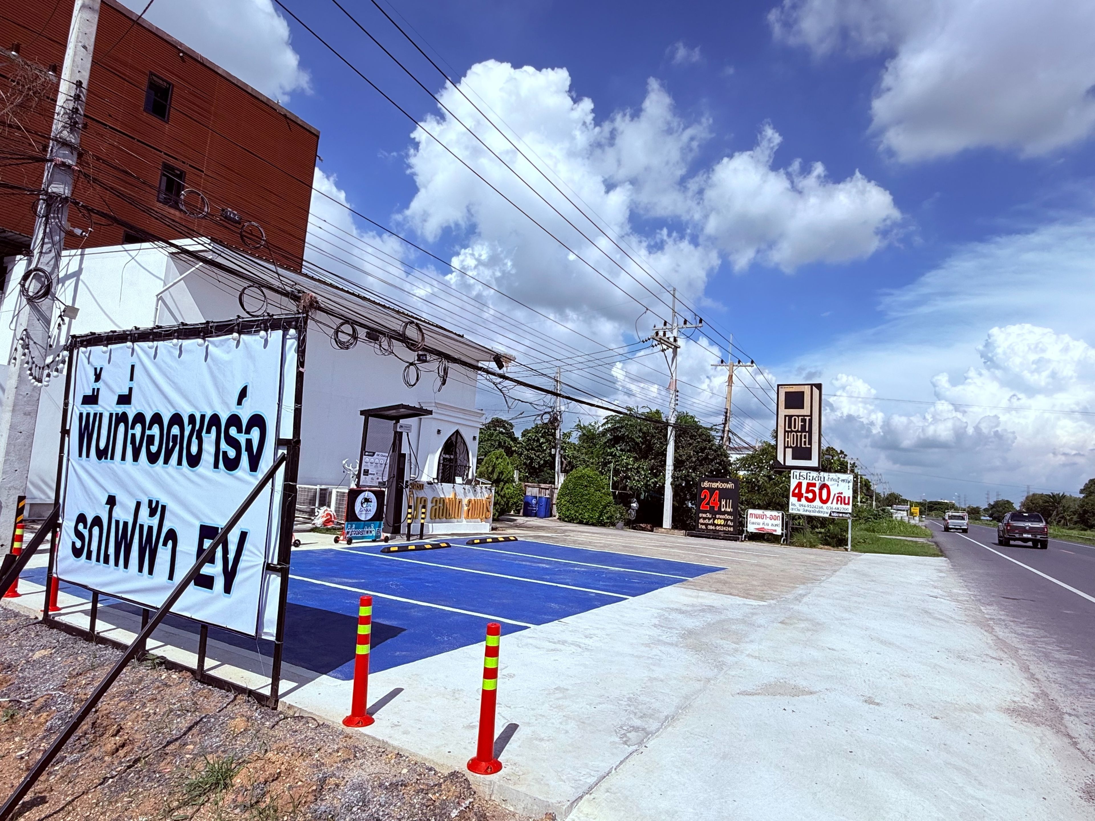 A hotel with a blue parking area, a signboard, and a building with a red brick facade.