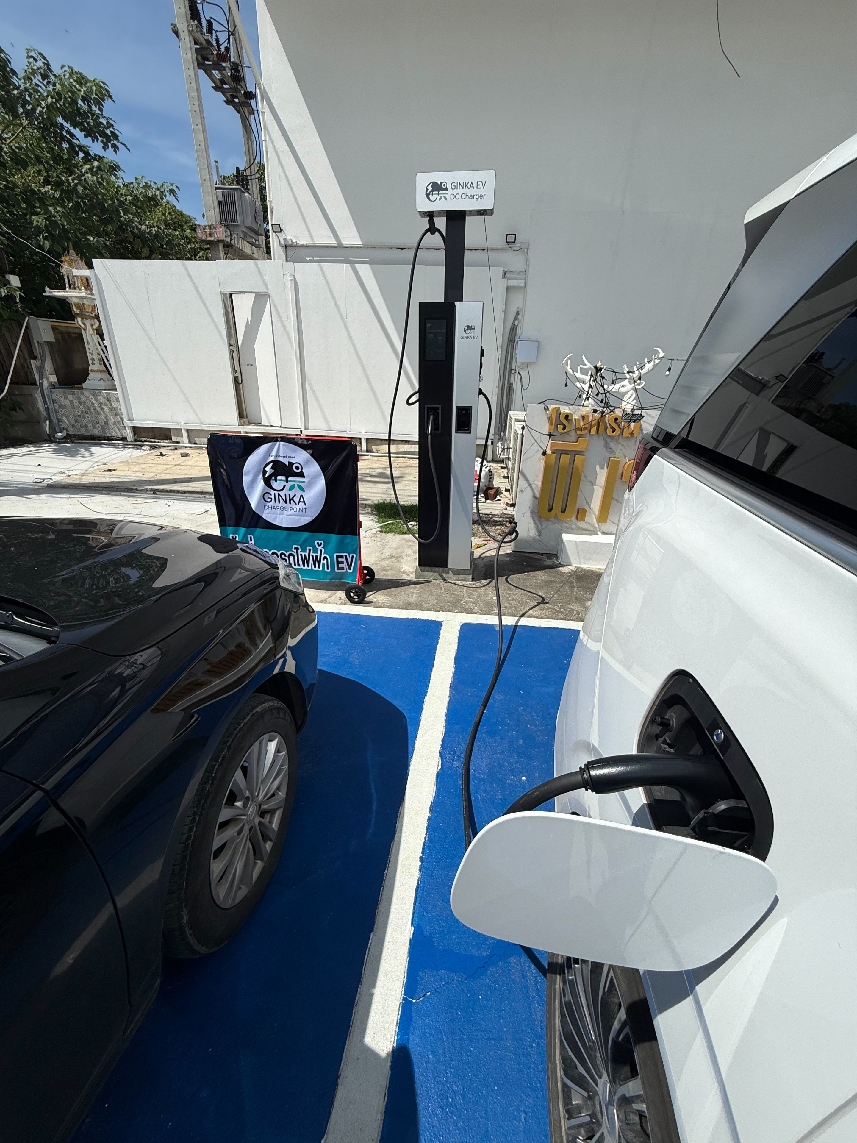 Un coche negro estacionado en una estación de carga para vehículos eléctricos, con un espacio de estacionamiento azul reservado para vehículos eléctricos.