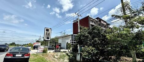 Un edificio con cartel de hotel, aparcamiento y una calle con coches.