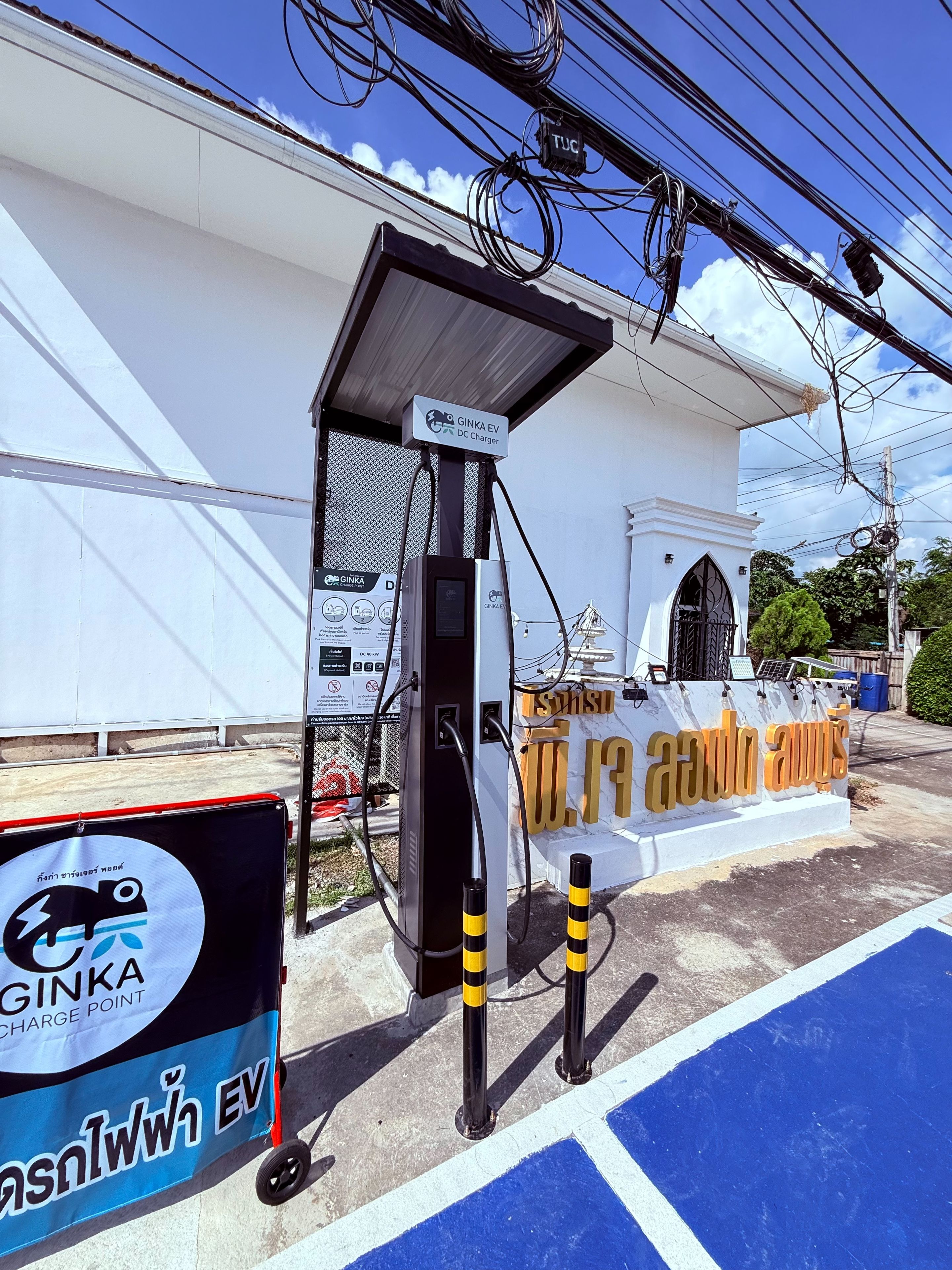 Una estación de carga para vehículos eléctricos con un letrero que indica que es un punto de carga Ginka.