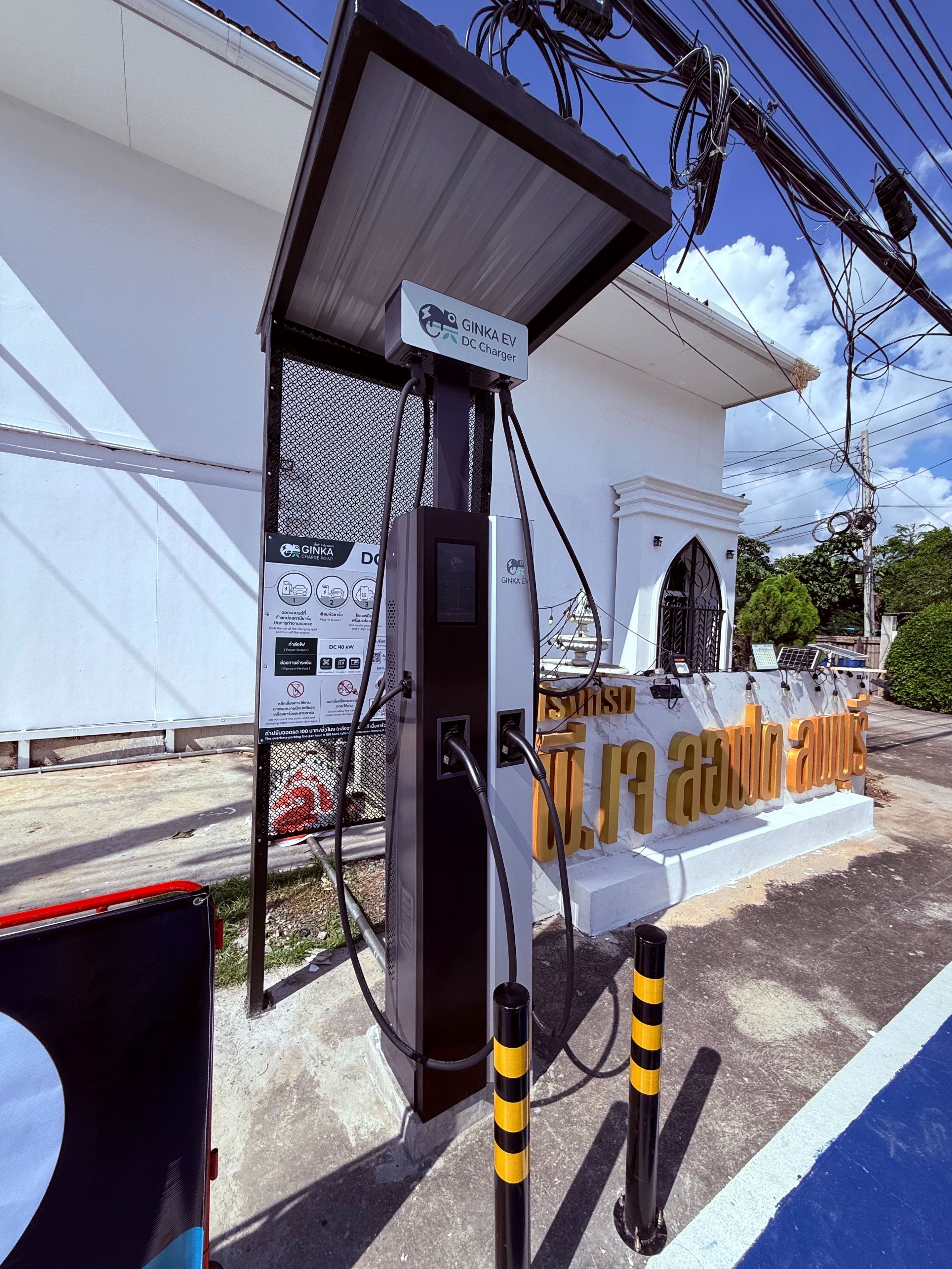 A Ginka EV DC Charger with a white building in the background.