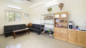 A reception area with a black sofa, a wooden cabinet, and a metal shelf unit. - Mei Cun B&B (Shoufeng)