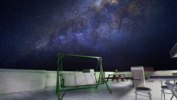 A rooftop terrace with a swing set, picnic tables, and chairs under a starry night sky. - Mei Cun B&B (Shoufeng)