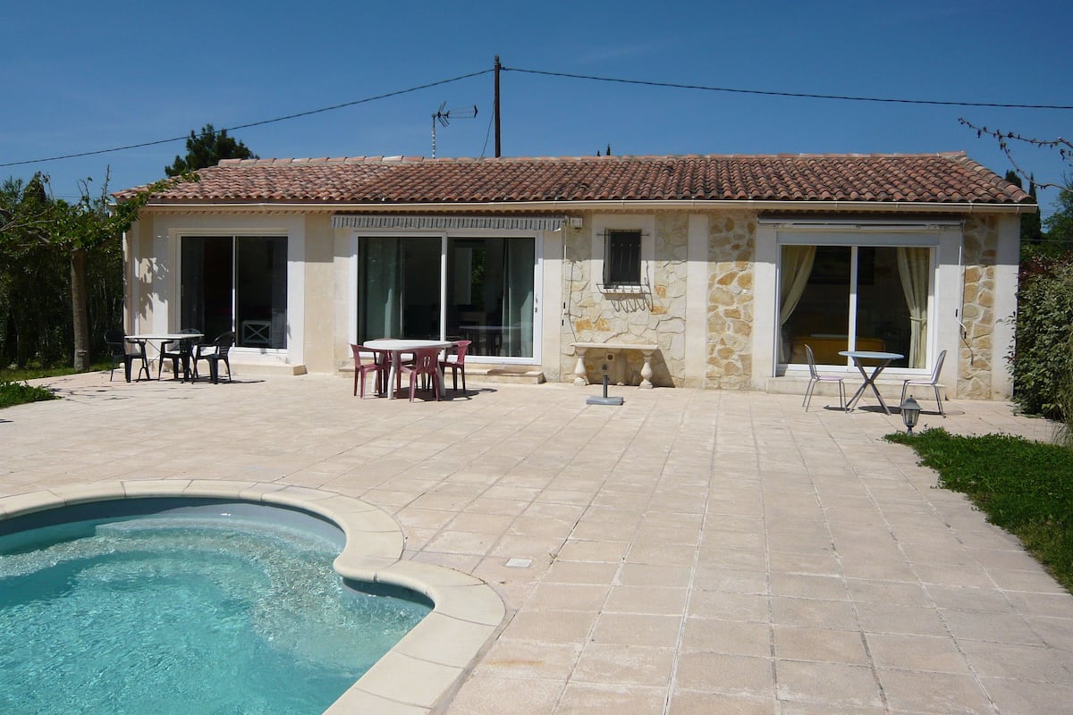 A house with a tiled roof, a swimming pool, and a patio with outdoor furniture.